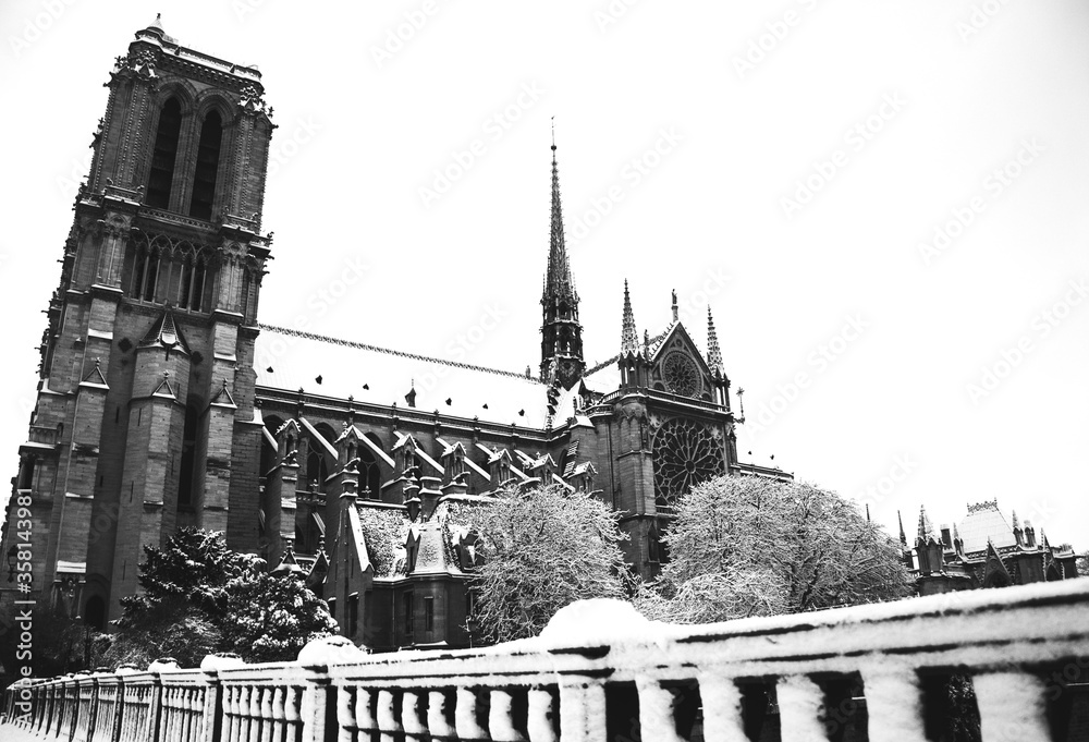 Historic photo Notre Dame cathedral (Paris, France) before fire in 2019 covered with snow in rare snowy winter day. View from the bridge. Black and white photo.