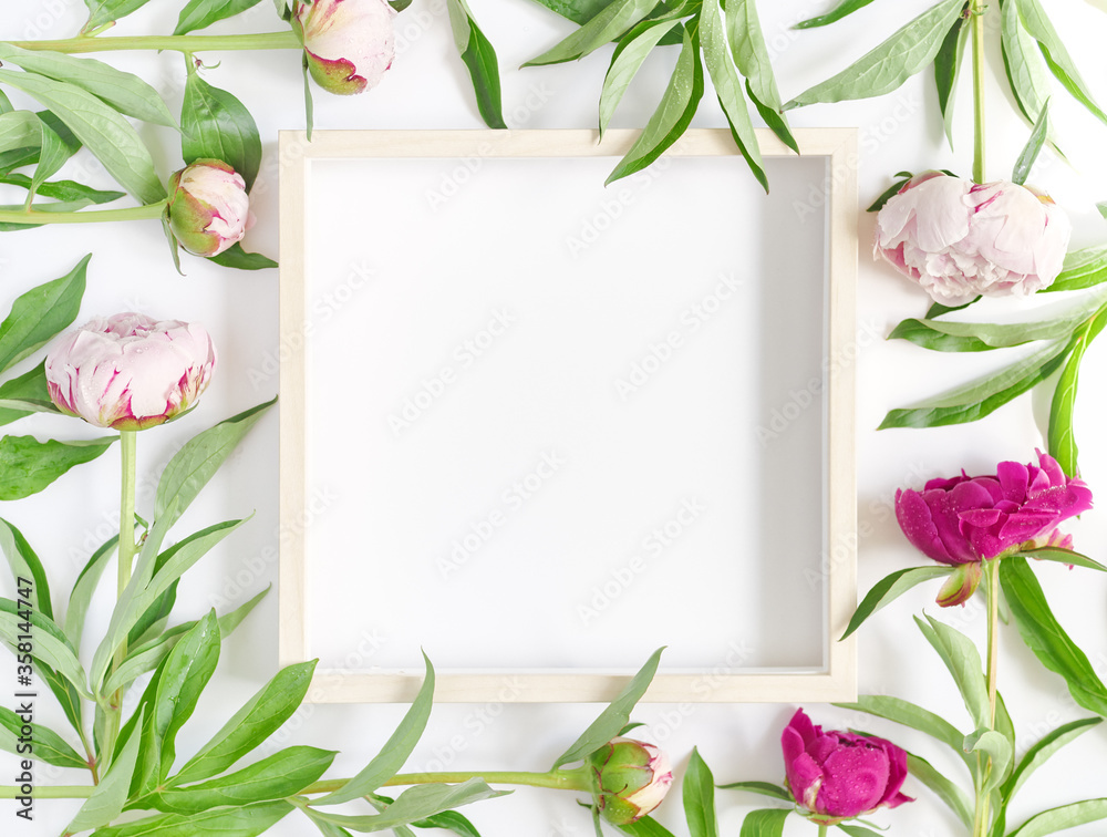 An empty wooden picture frame and fresh peonies are on a white background. Flower composition. Flat lay. Top view. Copy space. An empty wooden picture frame and fresh peonies are on a white background. Flower composition. Flat lay. Top view. Copy space.