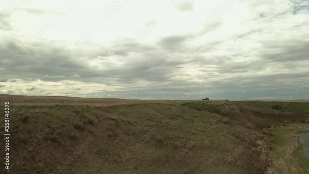 Flying Over The Field With A Farming Tractor Seeding In Saskatchewan, Canada. - aerial drone Flying Over The Field With A Farming Tractor Seeding In Saskatchewan, Canada. - aerial drone