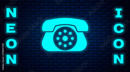 Glowing neon Telephone icon isolated on brick wall background. Landline phone. Vector Illustration