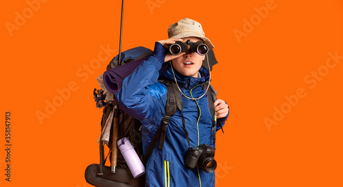 Excited backpacker looking towards camera through binoculars