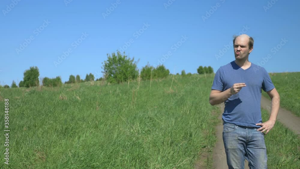 bald villager in tarpaulin boots walking on a field road bald villager in tarpaulin boots walking on a field road