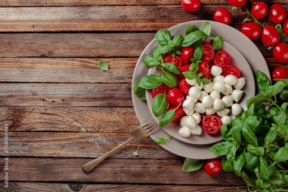 Caprese salad with tomato, mini mozzarella and basil on a old wooden table. Caprese salad with tomato, mini mozzarella and basil on a old wooden table.