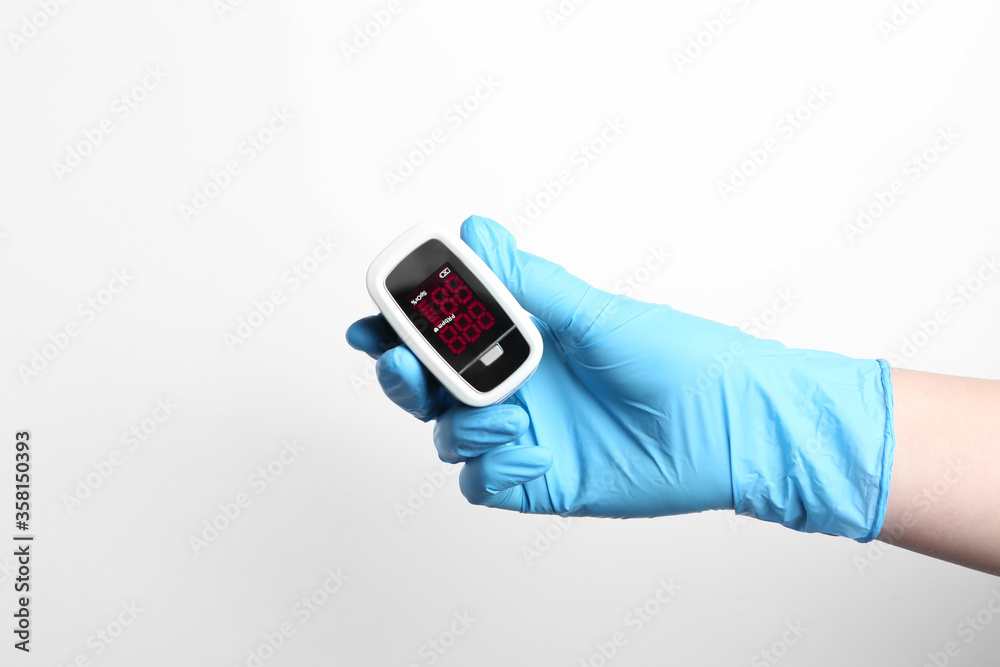 Doctor in gloves holding fingertip pulse oximeter on white background, closeup Doctor in gloves holding fingertip pulse oximeter on white background, closeup