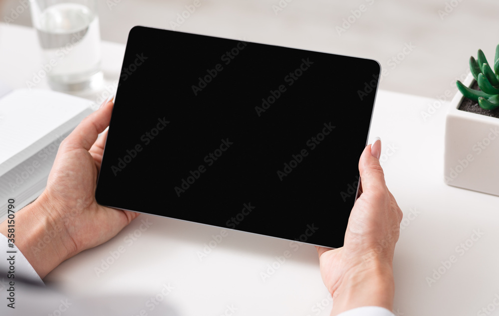 Watching video lesson or online webinar. Woman hands holds tablet with blank screen