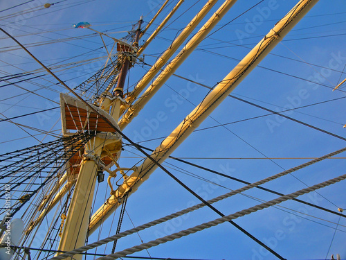Masts of a sailing ship seen from below against the blue sky
