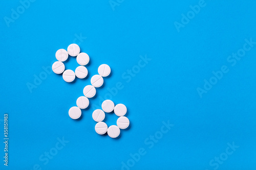 A percent sign of drugs on a blue background top view with copy space, a conceptual background on a medical theme and a depiction of percentages for sales or indication of dosages.