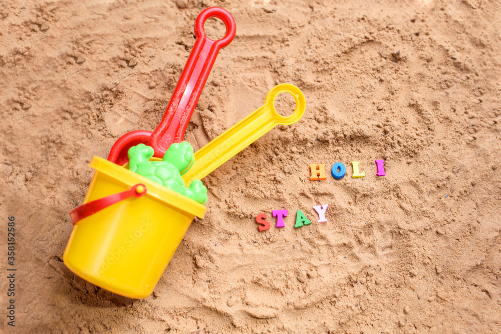 Beach sand with toys for the baby, water, the word holi saty in colored letters. Beach sand with toys for the baby, water, the word holi saty in colored letters.
