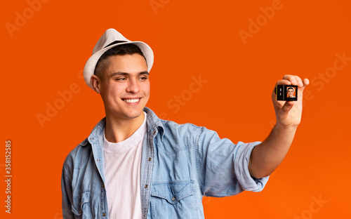 Smiling young guy tourist using action camera