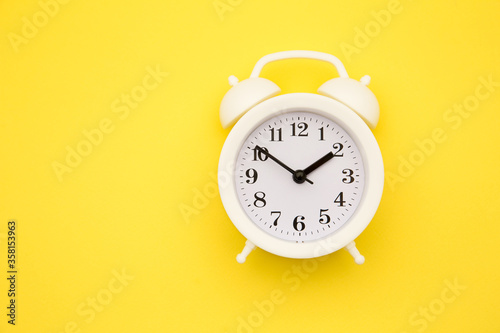 White alarm clock Isolated on yellow trendy background. Rest hours time of life good morning night wake up awake concept.