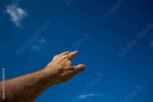 A man's hand points to the blue sky. symbol of faith, goal.