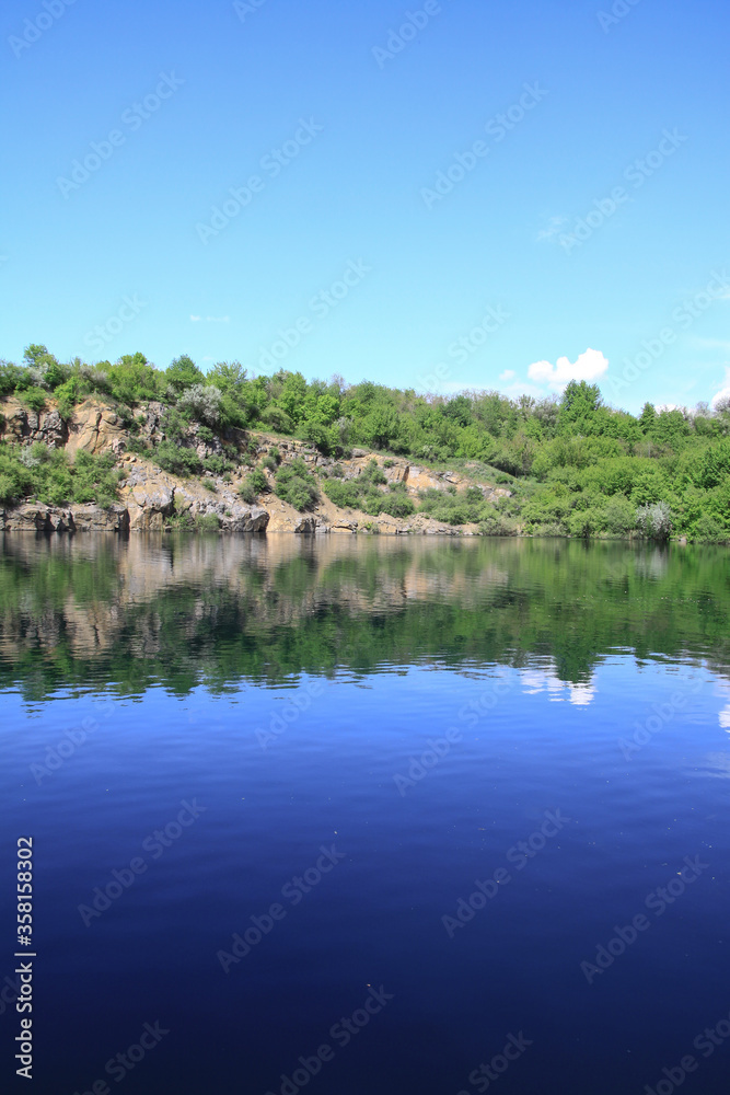 Naklejka premium Beautiful river in the highlands in summer. Lake in an ecologically clean park reserve on a background of hills. A pretty landscape in the spring. Stock photo for design