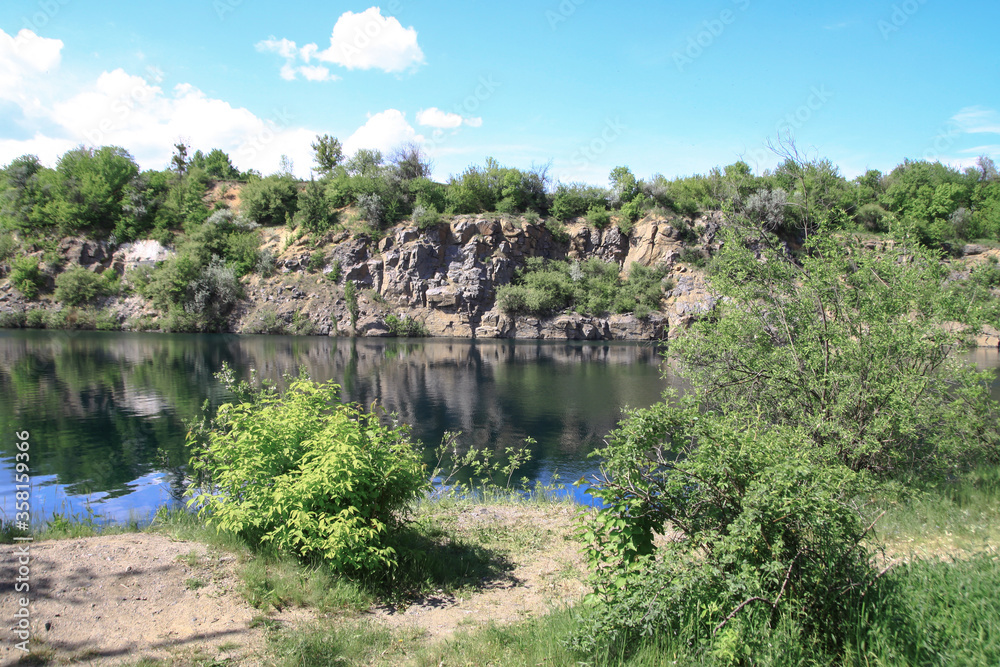 Fototapeta premium Beautiful river in the highlands in summer. Lake in an ecologically clean park reserve on a background of hills. A pretty landscape in the spring. Stock photo for design