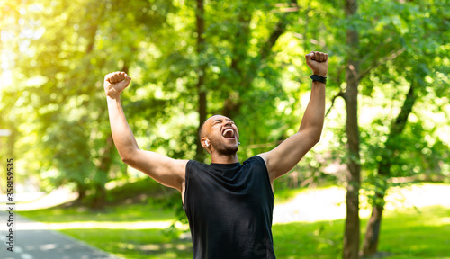 Victorious black sportsman rising his hands in triumph during his training at park