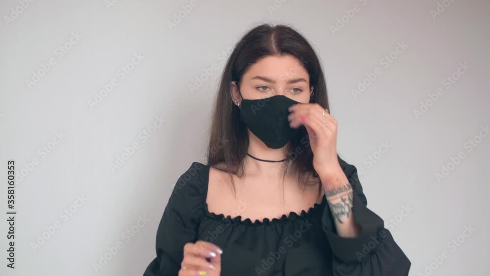 YOung brunette puts on balck mask and adjusts it.