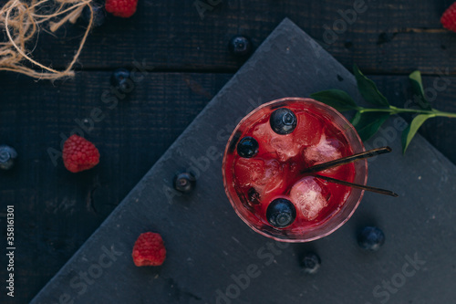Tablou pe pânză Fruity cocktail drink decorated with frozen or fresh raspberry, strawberry, rosemary, ice and soda