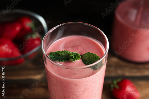 Tasty strawberry smoothie with mint in glass on table, closeup