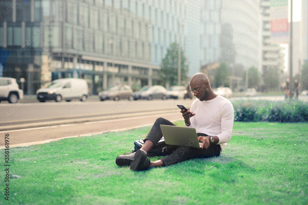 young man in a park in the city uses smartphone and laptop young man in a park in the city uses smartphone and laptop
