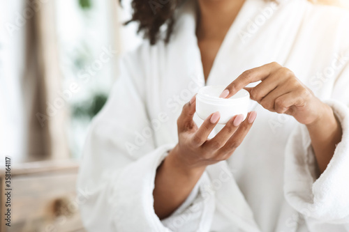 Unrecognizable black woman holding jar with organic natural cream in her hands