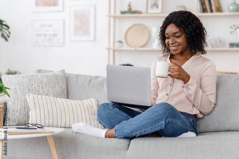 Leisure Concept. Young woman relaxing at home on the couch, having coffee and using laptop computer, copyspace Leisure Concept. Young woman relaxing at home on the couch, having coffee and using laptop computer, copyspace