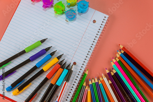 School supplies ,colored pencils top border on a pink background