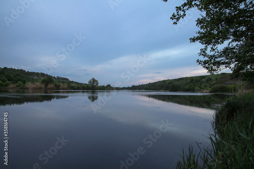 Fototapeta Naklejka Na Ścianę i Meble -  Beautiful river in the highlands in summer. Lake in an ecologically clean park reserve on a background of hills. A pretty landscape in the spring. Stock photo for design