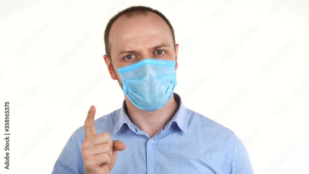 Handsome european man in protective mask saying no by waving his finger. Handsome european man in protective mask saying no by waving his finger.