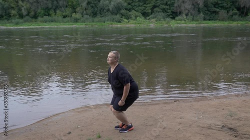 Fat guy jumping on the background of the river. photo