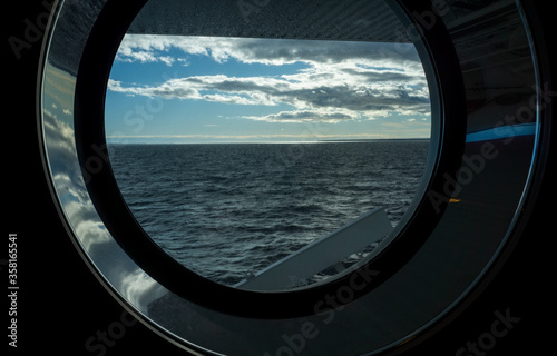 Sea view through the porthole of a passenger ferry in cloudy, calm weather