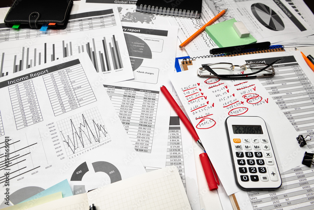 Top view of office employee's desk - work with financial reports, analysis and accounting, tables and graphs, various office items for bookkeeping Top view of office employee's desk - work with financial reports, analysis and accounting, tables and graphs, various office items for bookkeeping