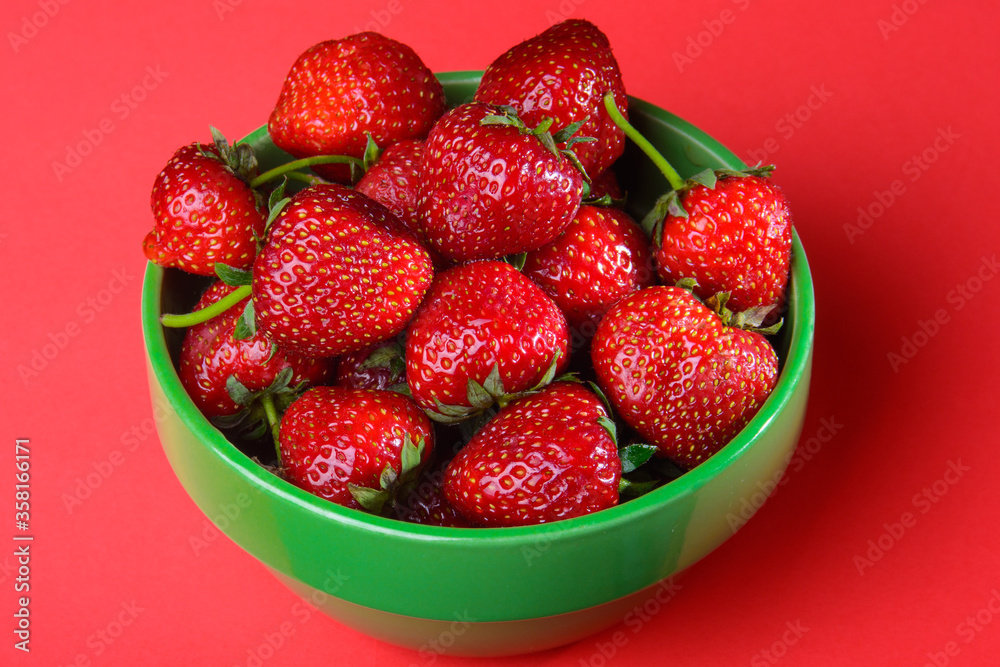 strawberries in green bowl on red background strawberries in green bowl on red background