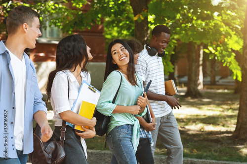 Фотография Joyful College Friends Walking Outdoors After Classes And Chatting