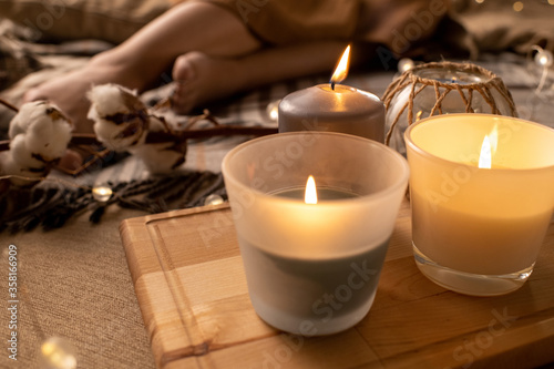 Close-up of burning smelling candles on wooden tray placed on bed for aromatherapy