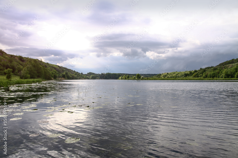 Landscape with a beautiful river and swans on a background of hills. Lake in the ecological zone in europe. Stock image for design.