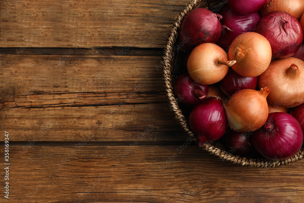 Onion bulbs in basket on wooden table, top view. Space for text Onion bulbs in basket on wooden table, top view. Space for text