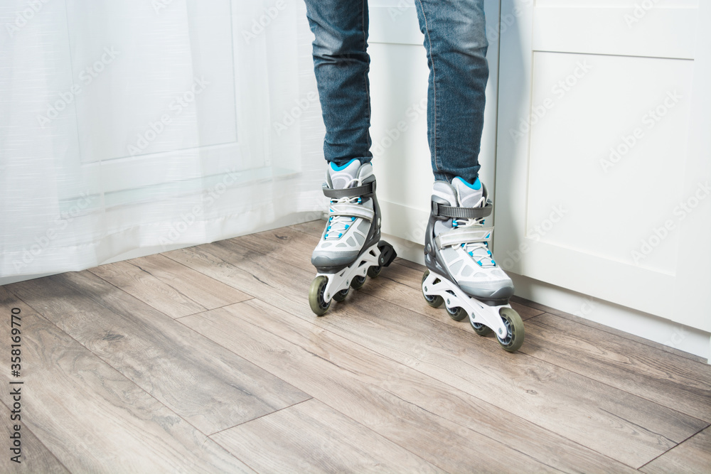 Two legs with jeans in roller skates standing at home on floor. Woman doing active sport at home in new equipment. Copy space Two legs with jeans in roller skates standing at home on floor. Woman doing active sport at home in new equipment. Copy space