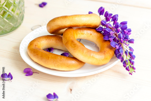 Sweet bagels and tender lupine flowers. Light composition with bright and purple flowers. A tender and romantic morning. photo