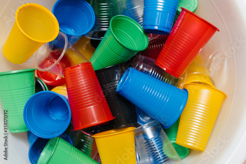 A large pile of multicolored plastic cups scattered on the floor. Pollution of the environment by human waste
