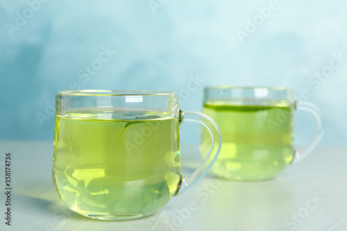 Cups of aromatic green tea on light table