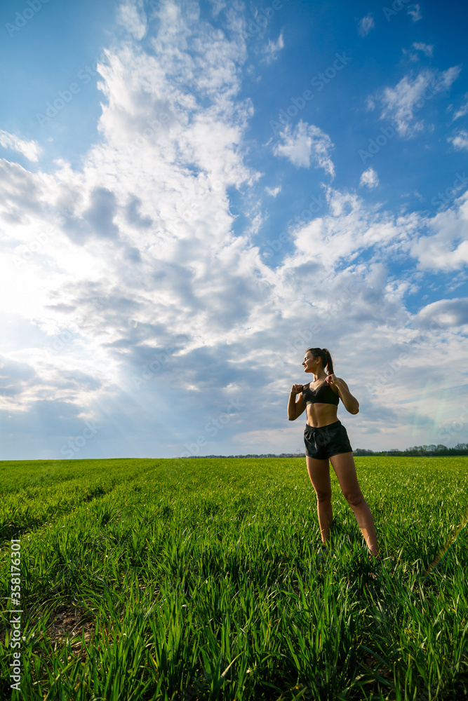 Healthy lifestyle concept. Young attractive woman in sportswear does stretching her hand before training on the nature against a blue sky. Muscle warming Healthy lifestyle concept. Young attractive woman in sportswear does stretching her hand before training on the nature against a blue sky. Muscle warming