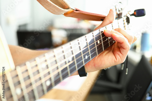 Man plays guitar, male hand holds neck guitar photo