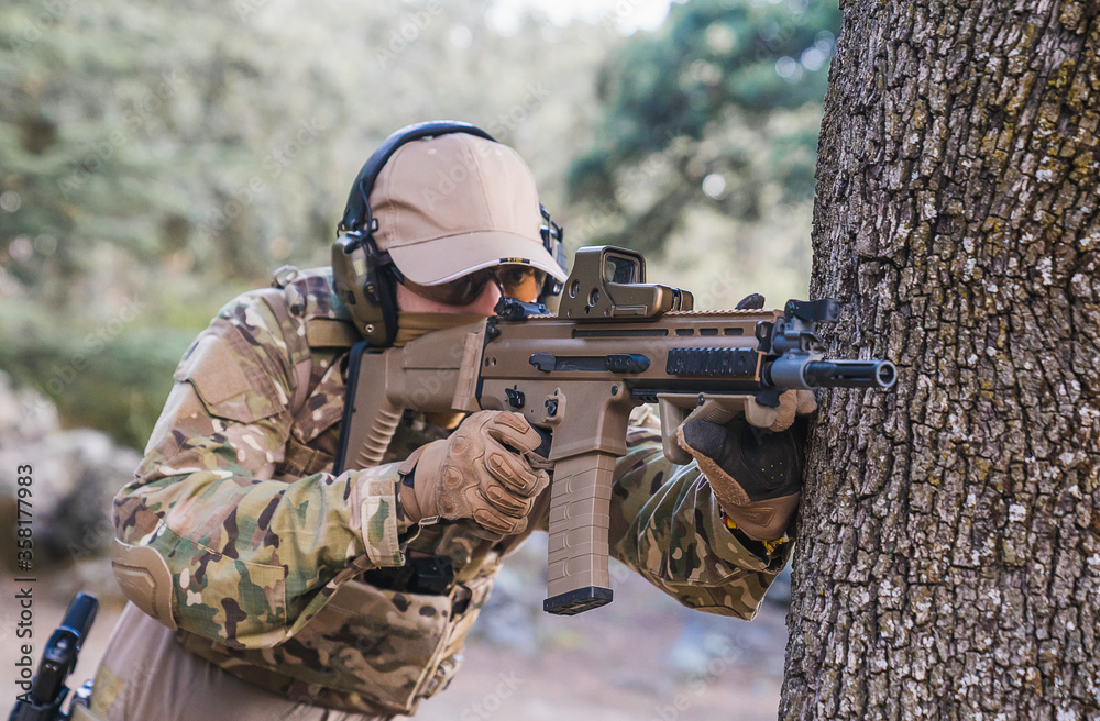 Marine pointing his assault rifle. Playing airsoft. Scar-L Assault Rifle. Soldier at gunpoint. Marine doing target practice. Weapons for war. Soldier. Marine. Cutting weapon range. Airsoft.