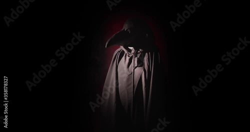 A black plague doctor entering a room in the dark
