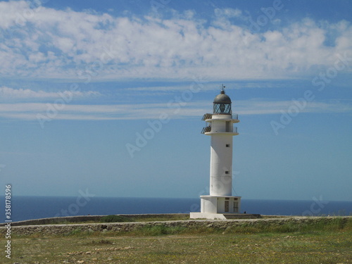 Seascape with the white lighthouse in Cap de Barbaria, Formentera island, Spain - blue sky with horizontal clouds