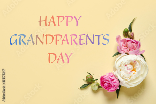 Beautiful peonies and phrase HAPPY GRANDPARENTS DAY on color background, flat lay © New Africa