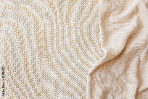 Two soft beige knitted blankets lying diagonally with copy space. Retro abstract boho scandinavian rustic background with cloth for decorative design. Cosy warm seasonal interior concept.