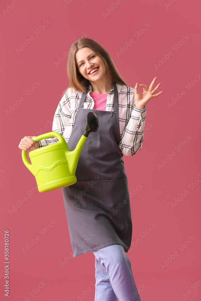 Young woman with watering can showing OK on color background Young woman with watering can showing OK on color background