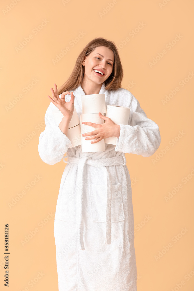 Young woman with many rolls of toilet paper showing OK on color background Young woman with many rolls of toilet paper showing OK on color background