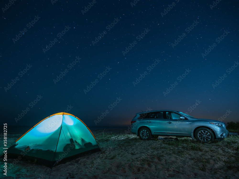 the car and illuminated tent on the beach in hight scene under star sky with copy space