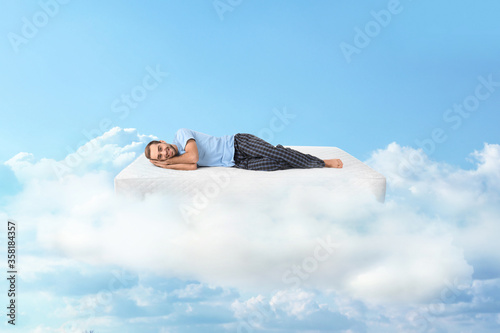 Young man lying on mattress in clouds